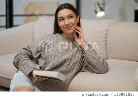 Dark-haired young woman with a book in hands Dark-haired young woman with a book in hands 136991833