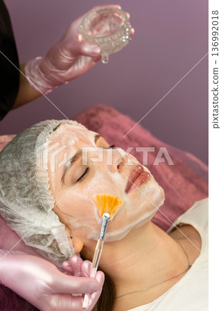 Esthetician fans foamy facial mask onto client's cheek Esthetician fans foamy facial mask onto client's cheek 136992018