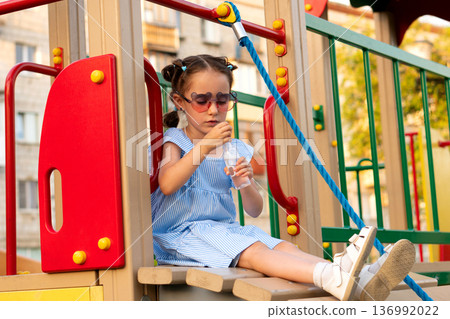 Seated girl prepares bubbles on slide platform at dusk 136992022