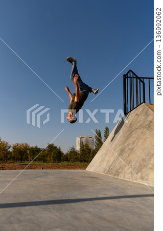 Man upside down mid-backflip during extreme urban freerunning Man upside down mid-backflip during extreme urban freerunning 136992062