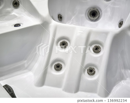 Hot tub interior with water jets and seating area for relaxation during a sunny afternoon outside a house Hot tub interior with water jets and seating area for relaxation during a sunny afternoon outside a house 136992234
