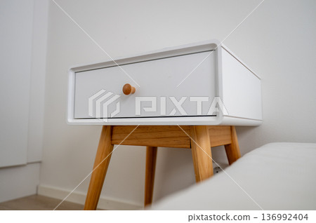 Minimalist bedside table with wooden legs in Scandinavian bedroom interior Minimalist bedside table with wooden legs in Scandinavian bedroom interior 136992404