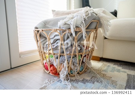 Woven rattan basket with cozy blankets and yarn in Scandinavian home interior Woven rattan basket with cozy blankets and yarn in Scandinavian home interior 136992411