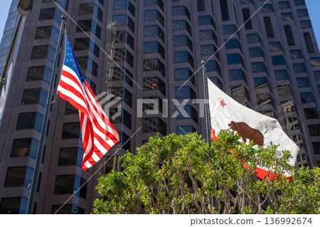 American and California flags waving in front of a modern building American and California flags waving in front of a modern building 136992674