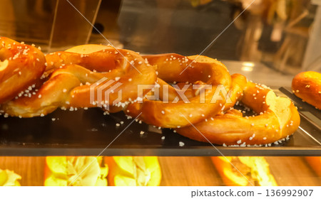 Freshly baked pretzels with salt crystals displayed in a glass case at a street bakery in paris, france 136992907