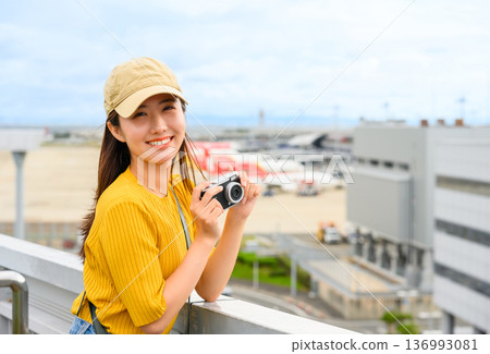 A woman holding a camera at the airport. Photo courtesy of Kansai International Airport (KIX). A woman holding a camera at the airport. Photo courtesy of Kansai International Airport (KIX). 136993081