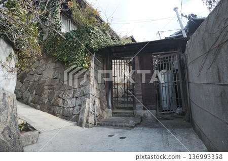 A sloping alley with stone walls and a wooden gate A sloping alley with stone walls and a wooden gate 136993358