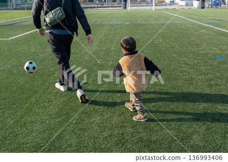 Child and father playing soccer Child and father playing soccer 136993406