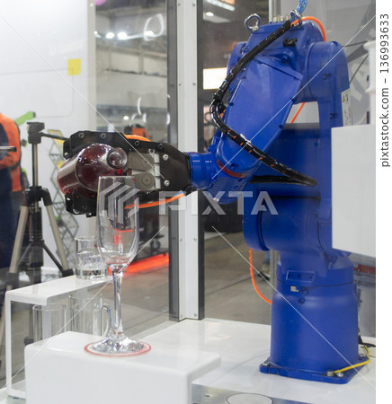Robotic manipulators. Robot pouring liquid drink from bottle into glass. Industrial robot. Robot arm hand. Industrial manipulators for variety welding, material handling, palletizing. Robotization 136993633