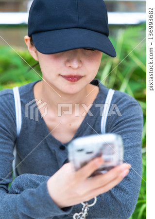 一位戴著帽子的女士正在使用智慧型手機。照片由關西國際機場(KIX)提供。 一位戴著帽子的女士正在使用智慧型手機。照片由關西國際機場(KIX)提供。 136993682