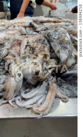 Market stall showcases glistening squid ready for purchase 136994258
