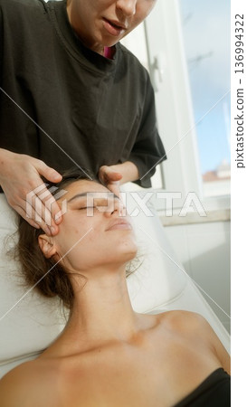 Intimate closeup of woman receiving soft facial massage with serum Intimate closeup of woman receiving soft facial massage with serum 136994322