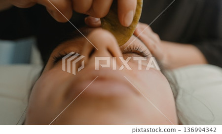 Precise eyebrow design using soft jade strokes in lively salon setting Precise eyebrow design using soft jade strokes in lively salon setting 136994342