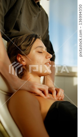 Serene woman receiving calming facial in warm sunlight ambiance Serene woman receiving calming facial in warm sunlight ambiance 136994350