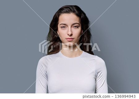 Portrait of beautiful serious teenage woman against grey studio background Portrait of beautiful serious teenage woman against grey studio background 136994943