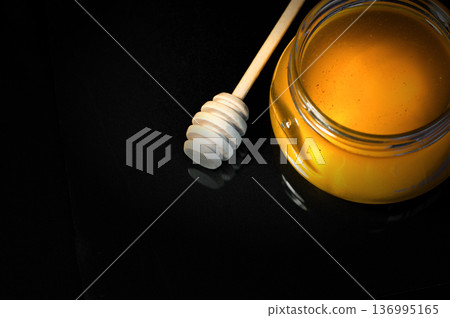 fresh honey in a jar and a honey spoon on a black background 136995165