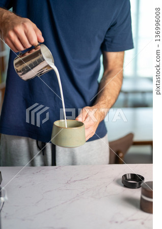 Man Pouring Frothy Milk Into A Cup To Make Creamy Coffee Beverage 136996008