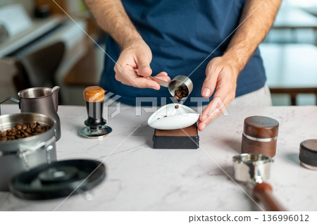 Home Barista Pouring Coffee Beans From A Scoop Into A Measure Bowl 136996012