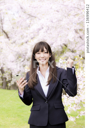 Office lady pumping her fist in front of the cherry blossoms Office lady pumping her fist in front of the cherry blossoms 136996412