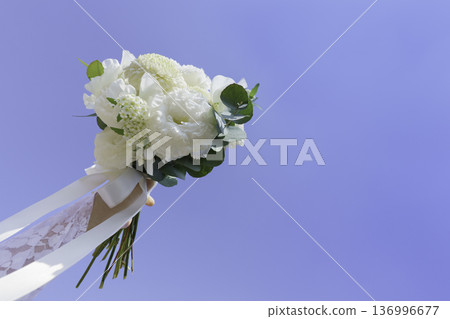 A wedding bouquet held up against the blue sky 136996677