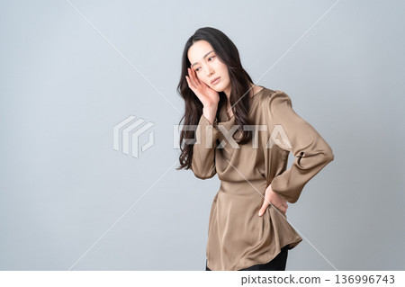 一位美麗的女性在灰色背景下進行護膚。 136996743