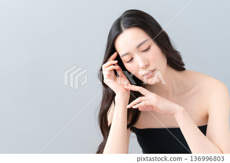 Beauty image of a woman doing skin care on a gray background 136996803