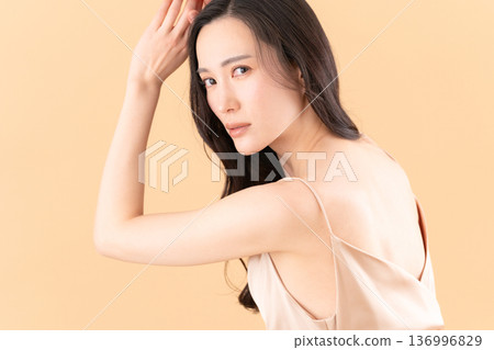 Beauty image of a woman doing skin care on a beige background 136996829