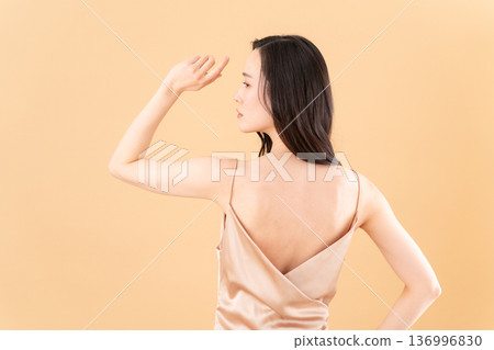 Beauty image of a woman doing skin care on a beige background Beauty image of a woman doing skin care on a beige background 136996830
