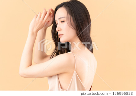 Beauty image of a woman doing skin care on a beige background 136996838