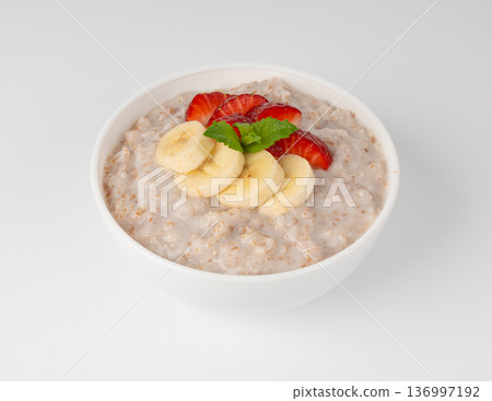 Cooked spelt in bowl isolated. Oatmeal milk porridge with fruits and berries Cooked spelt in bowl isolated. Oatmeal milk porridge with fruits and berries 136997192