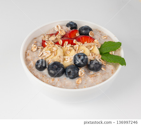Cooked spelt in bowl isolated. Oatmeal milk porridge with fruits and berries 136997246