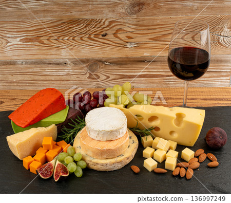 Cheese plate of color cheeses variety, yellow, white and blue gorgonzola platter with red wine glass Cheese plate of color cheeses variety, yellow, white and blue gorgonzola platter with red wine glass 136997249