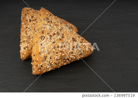 Triangular bun closeup. Wheat bread with sesame and flax seeds, healthy whole grain bakery Triangular bun closeup. Wheat bread with sesame and flax seeds, healthy whole grain bakery 136997519