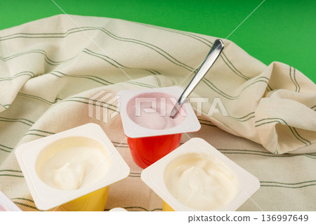 Yogurt cups set, pink and yellow fruit yoghurt in plastic pots, milk pudding container with spoon 136997649