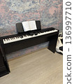 A black digital piano with open sheet music and headphones stands in a room with floral wallpaper, music education, creative hobby, home interior. 136997710