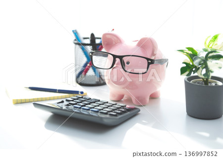 Smart piggy bank wearing glasses, using calculator Smart piggy bank wearing glasses, using calculator 136997852