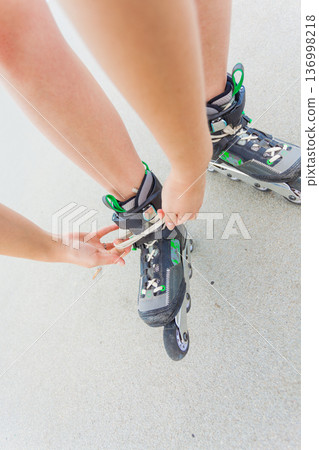 Woman putting roller skates on Woman putting roller skates on 136998218