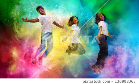 Three friends jumping in vibrant Holi powder explosion. Three friends jumping in vibrant Holi powder explosion. 136998365