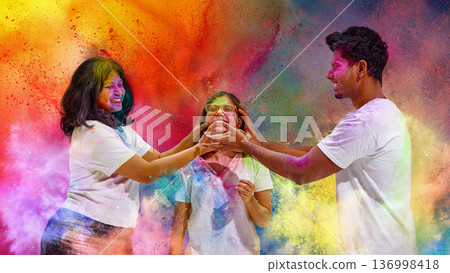 Three friends playfully smearing colors on each other at Holi festival. 136998418