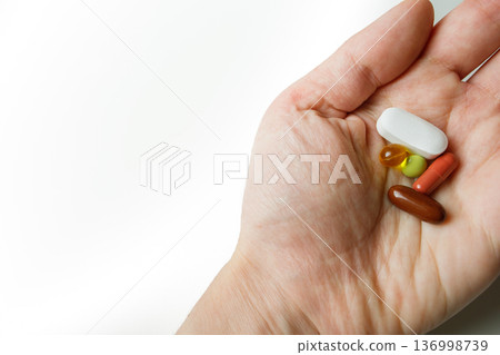 Colorful pills, tablets, capsules in woman hand close up with white background. Healthcare and medicine. Colorful pills, tablets, capsules in woman hand close up with white background. Healthcare and medicine. 136998739