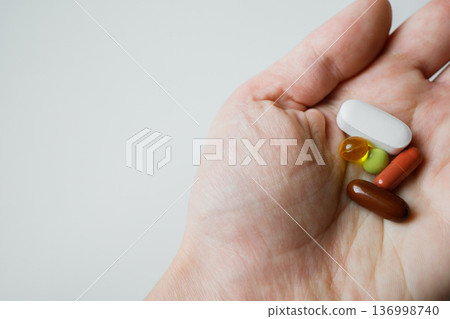 Colorful pills, tablets, capsules in woman hand close up with white background. Healthcare and medicine. Colorful pills, tablets, capsules in woman hand close up with white background. Healthcare and medicine. 136998740