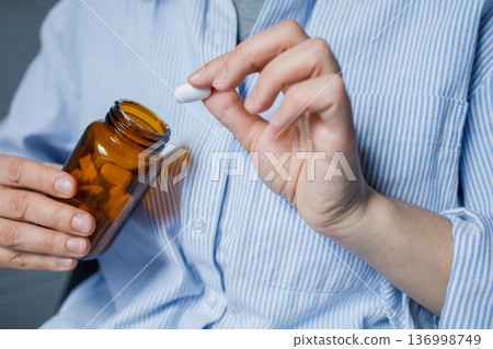 Woman taking one tablet from brown glass bottle with pills. Taking medication at home, disease prevention, taking antidepressants, vitamins, dietary supplements. Healthcare and medicine Woman taking one tablet from brown glass bottle with pills. Taking medication at home, disease prevention, taking antidepressants, vitamins, dietary supplements. Healthcare and medicine 136998749