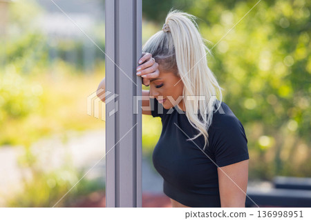 Woman resting outdoors during workout session, reflecting and recovering energy 136998951