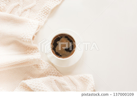Morning breakfast, cup of coffee and white cozy scarf on a white. Morning breakfast, cup of coffee and white cozy scarf on a white. 137000109