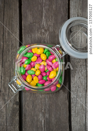Colorful sweet candy in glass jar on wooden background. Colorful sweet candy in glass jar on wooden background. 137000127