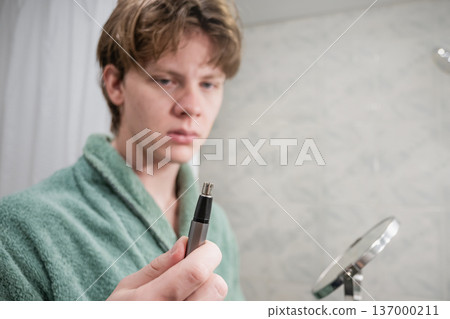Man holding nose trimmer in bathroom mirror Man holding nose trimmer in bathroom mirror 137000211