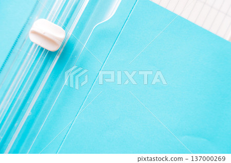 Paper trimmer detail with blue cardstock, clean minimal stationery background Paper trimmer detail with blue cardstock, clean minimal stationery background 137000269