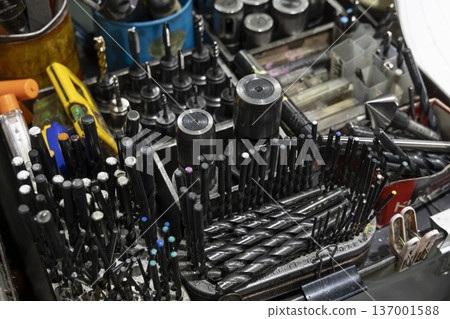 Numerous drill bits and tools neatly arranged on a workbench 137001588