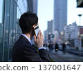 一位年輕的商人正在城市裡打電話。 137001647