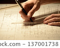 The hands of a Japanese architect drawing architectural drawings at night 137001738